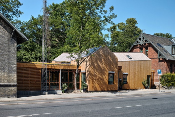 Billedet viser en træbygning mellem to murstenshuse.