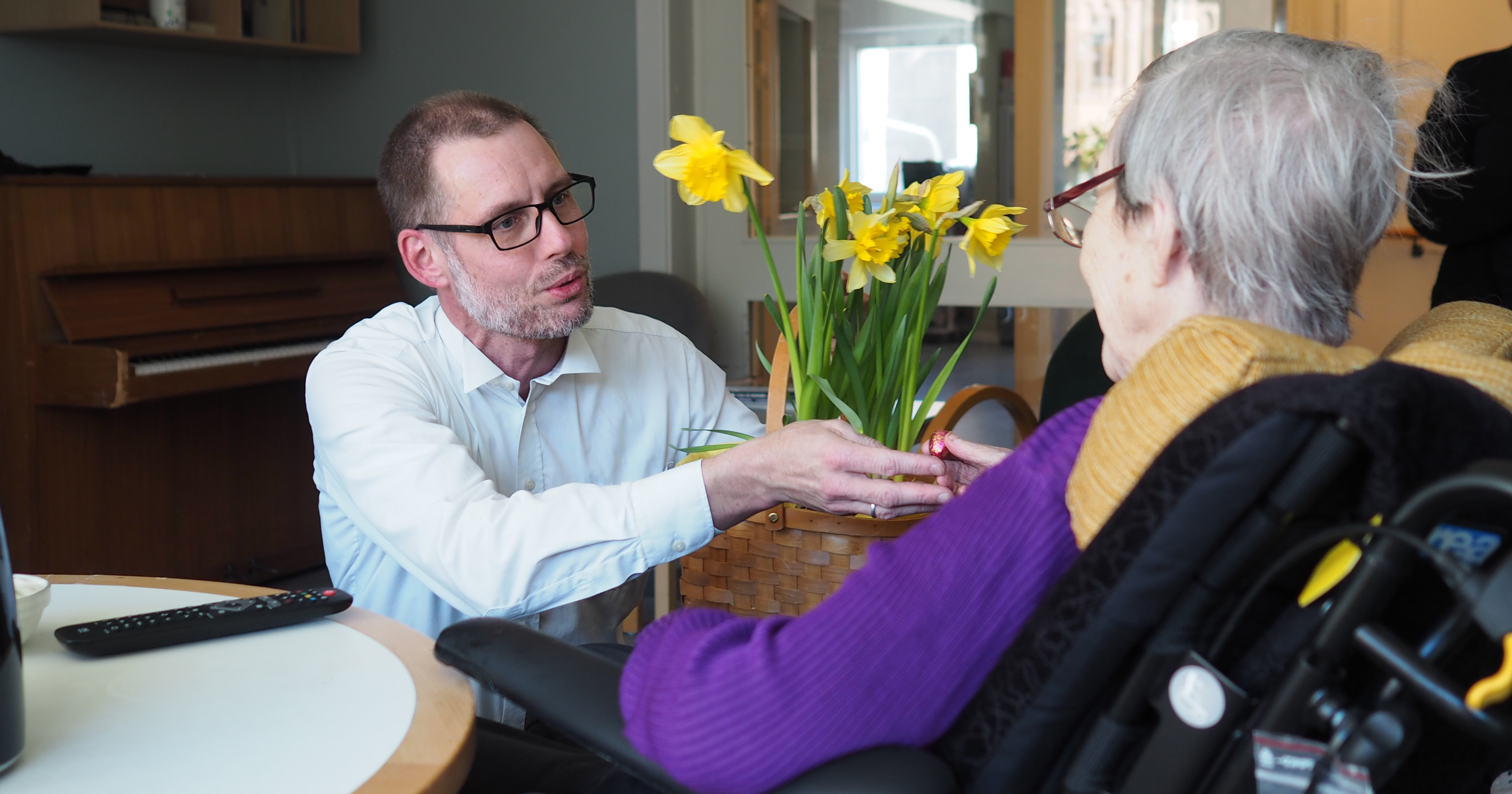 Jan Nilsson viser påskeliljer til en plejehjemsbeboer.