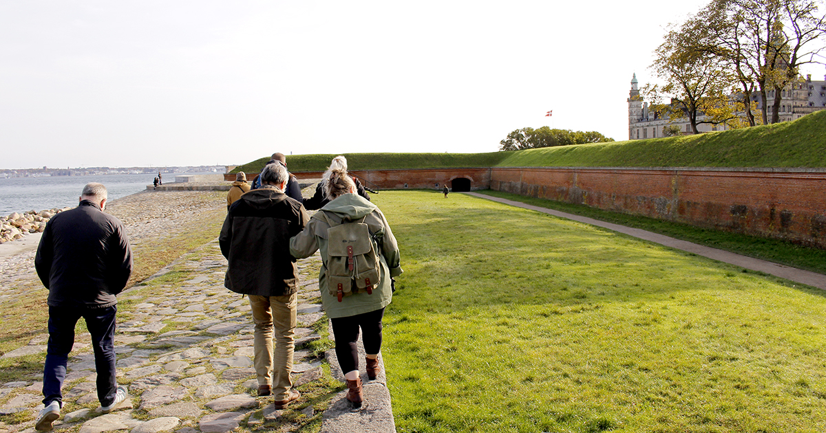 Billedet viser en gruppe mennesker, der går sammen i nærheden af Kronborg.