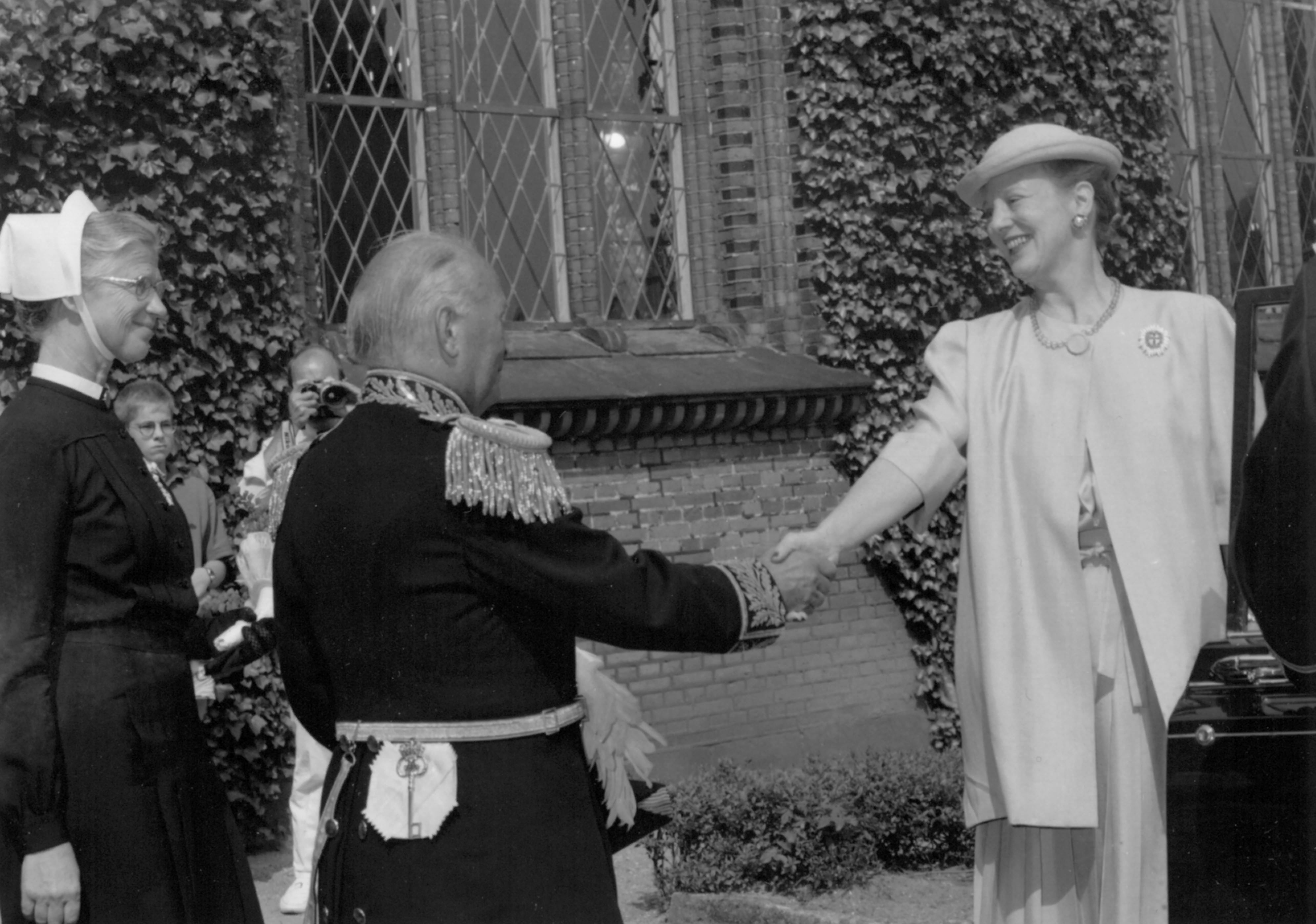 Billedet viser dronningen, der hilser på en mand og en diakonisse.