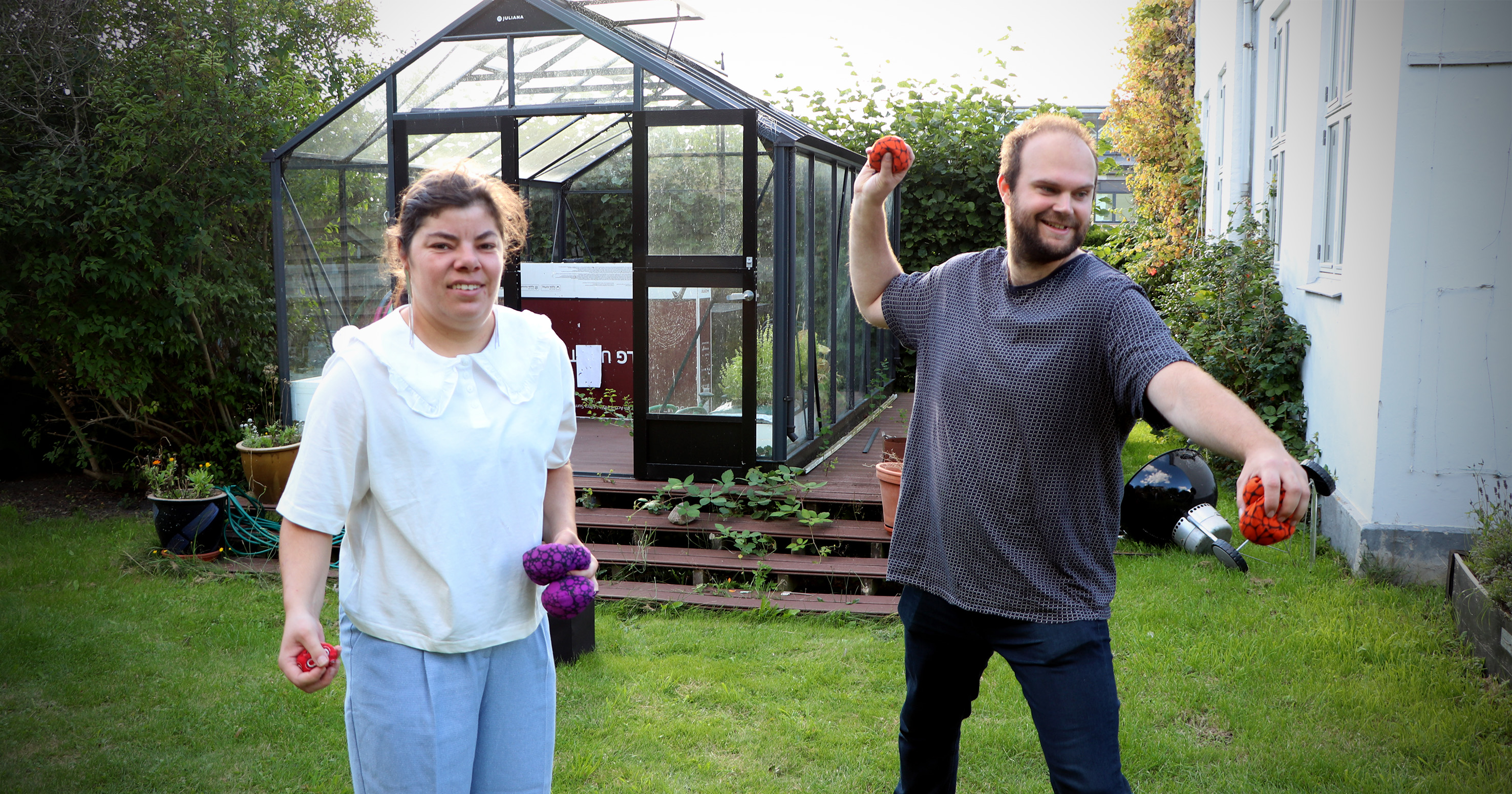 Lisa Baumann står sammen med Andreas Foss i haven. De spiller et spil med stofbolde.