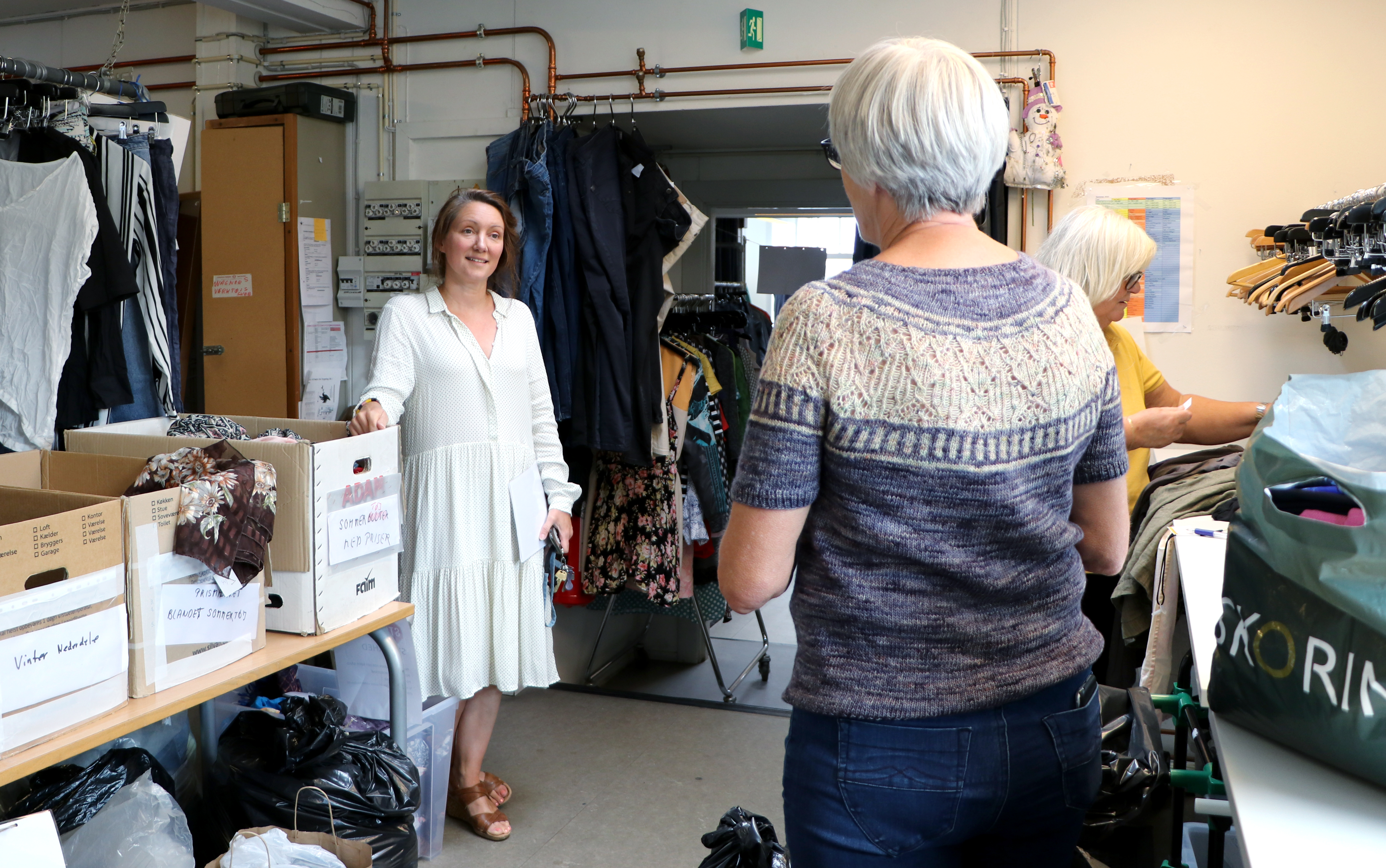 Billedet viser Trine Høst, der taler med en frivillig på Loppeshoppens lager.