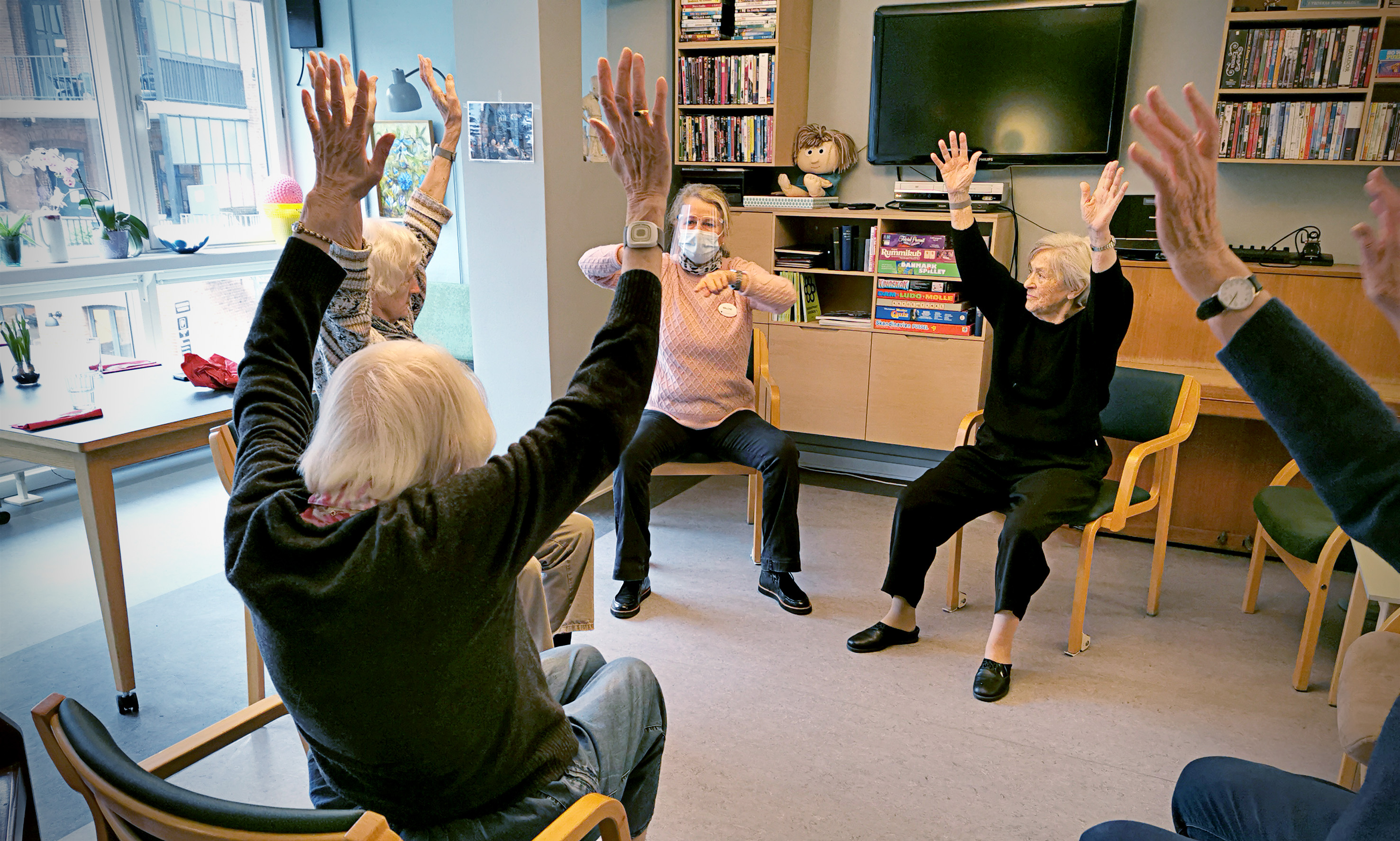 En gruppe ældre mennesker laver stolegymnastik.