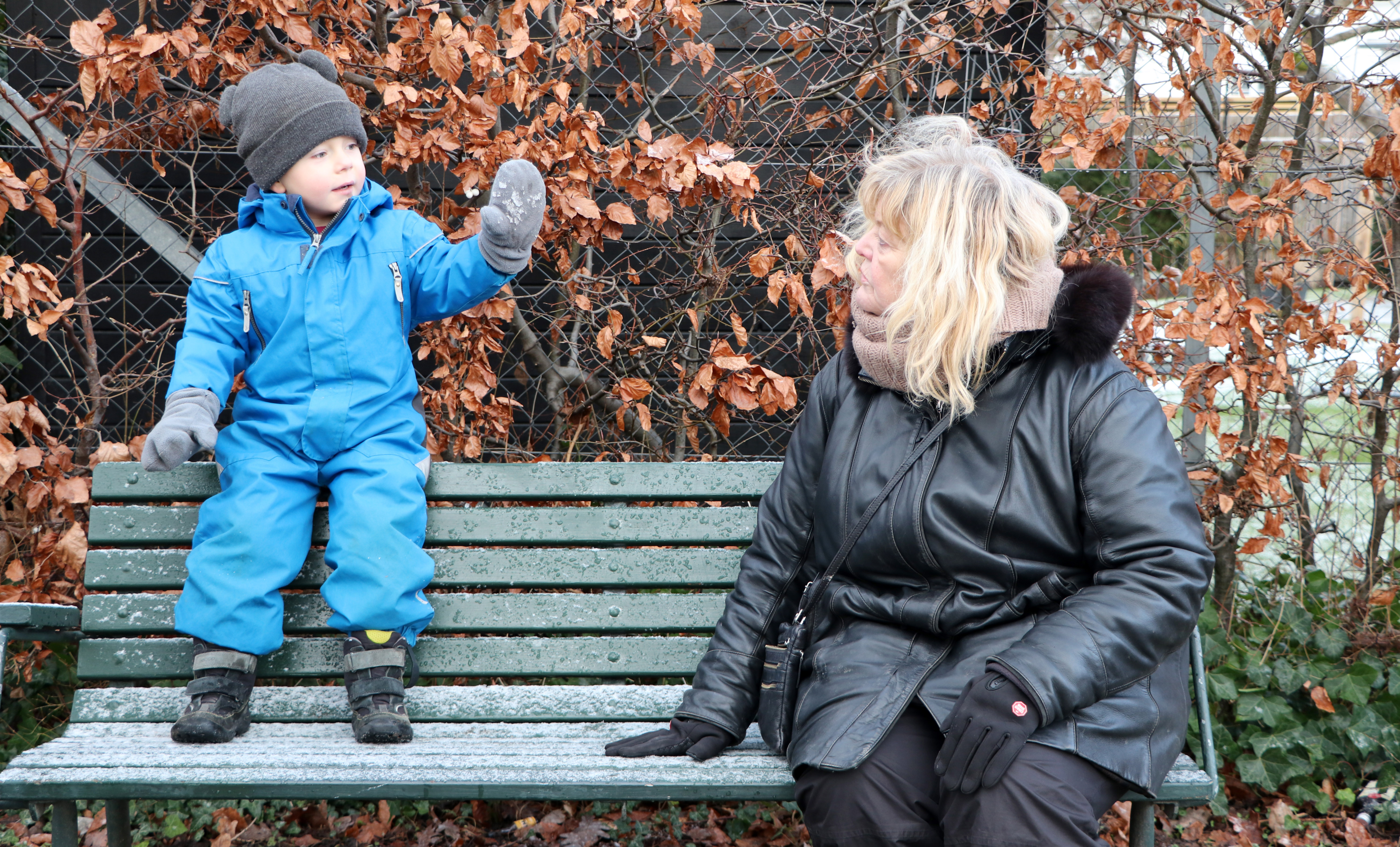 Et barn og en voksen sidder på en bænk.