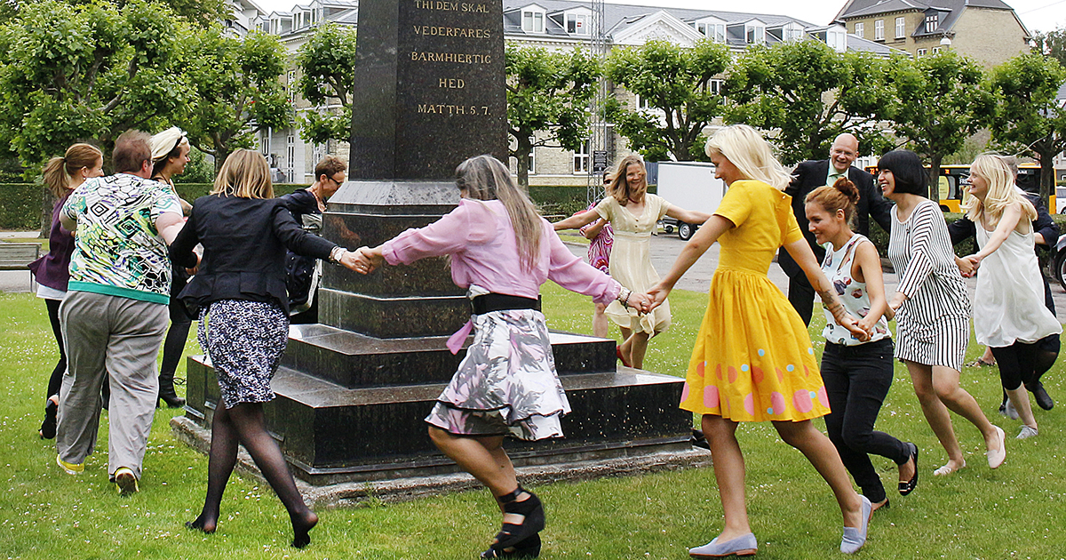 En gruppe dimittender danser om en buste af Dronning Louise.