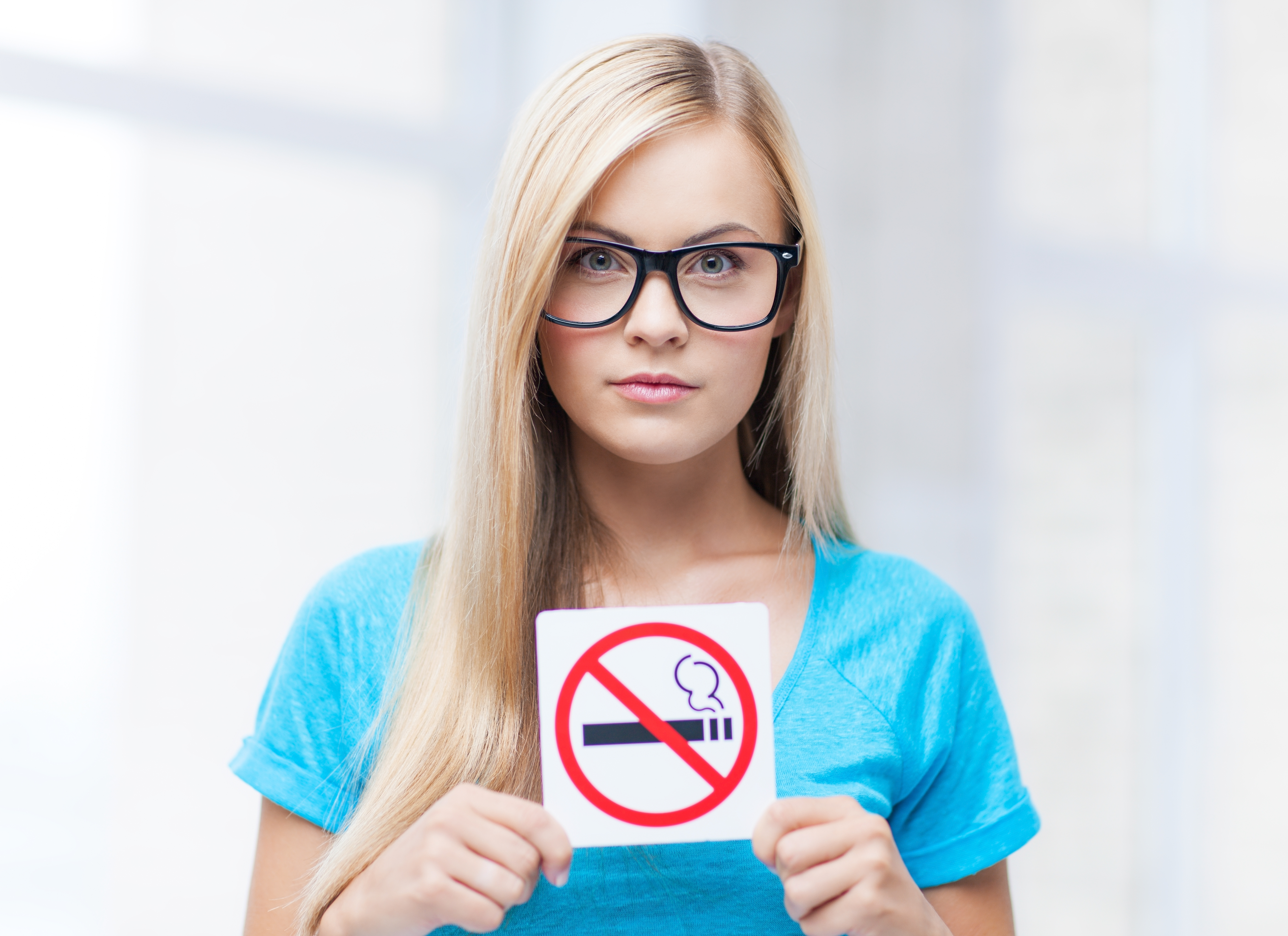 En piger holder et rygning forbundt-skilt.