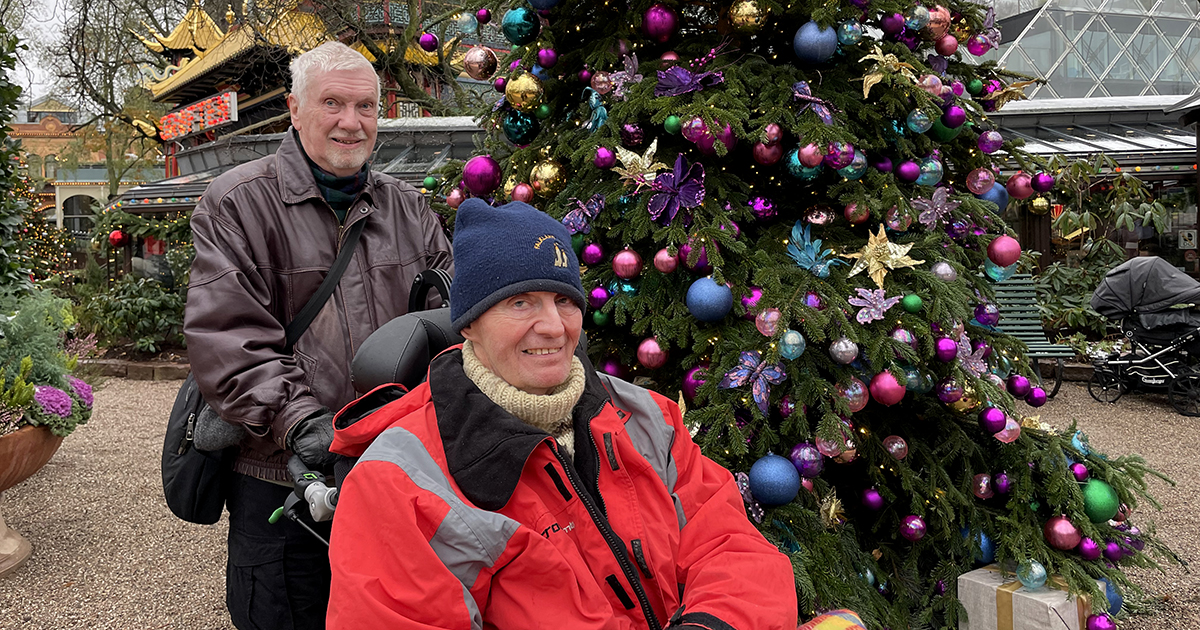 To mænd foran et juletræ.