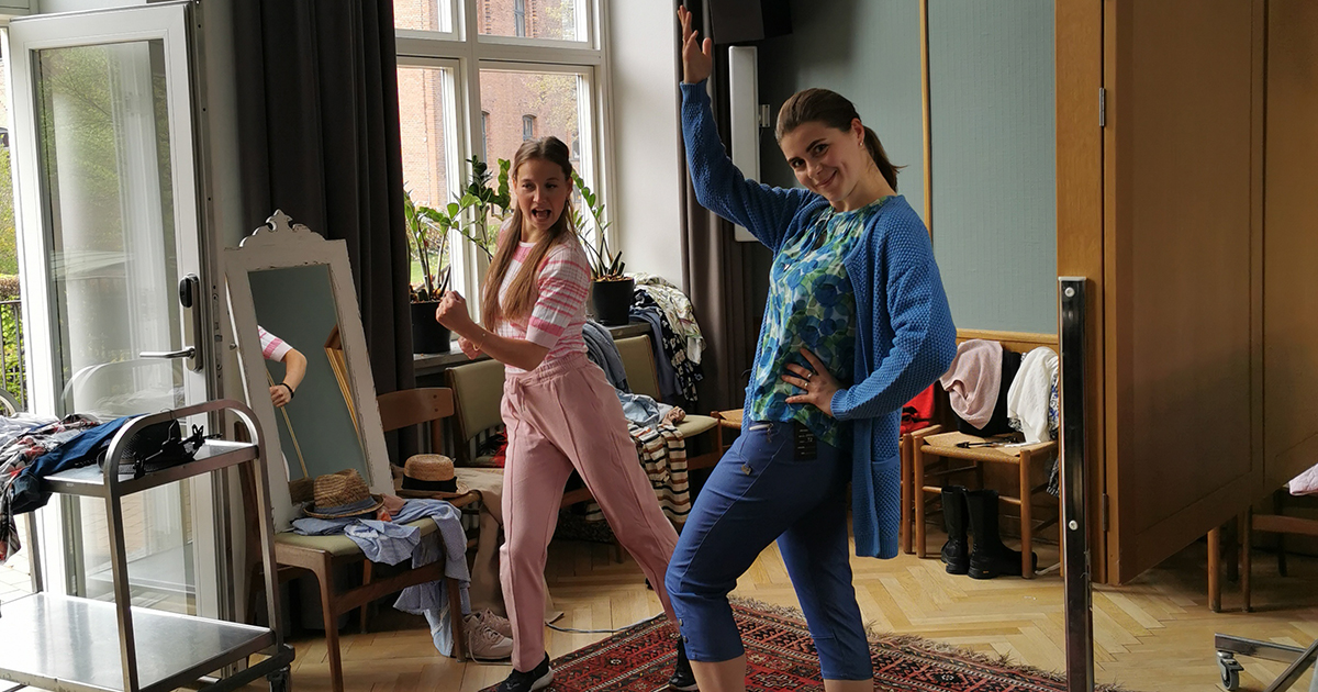 Billedet viser to kvinder som danser og viser tøj frem.