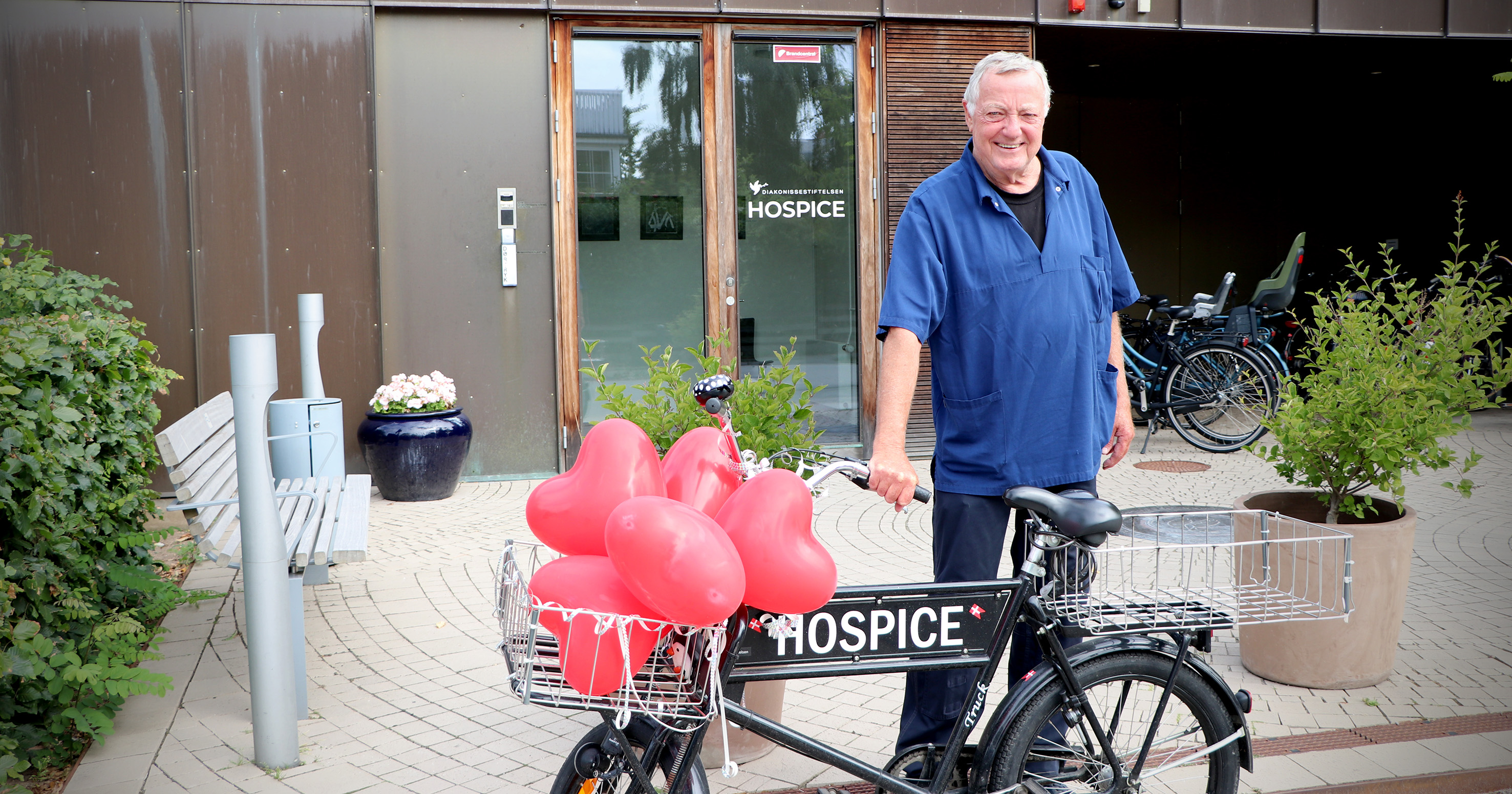 En mand står ved en cykel pyntet med balloner.