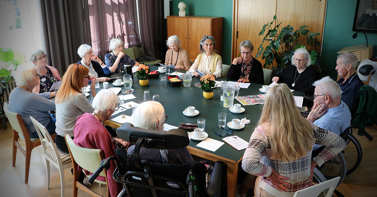 På billedet ser man ældre mennesker rundt om et stort bord.